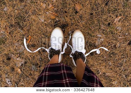 Female Legs In White Boots In The Forest With Cones. Tourism Tourism Concept. Coniferous Forest.