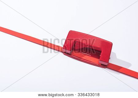 High Angle View Of Red Holepunch And Paper Strip On White Background
