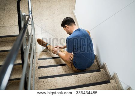 Man Sitting On Staircase After Slip And Fall Accident