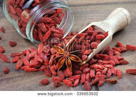 Goji Berries In A Wooden Scoop. Dried Goji In A Glass Jar
