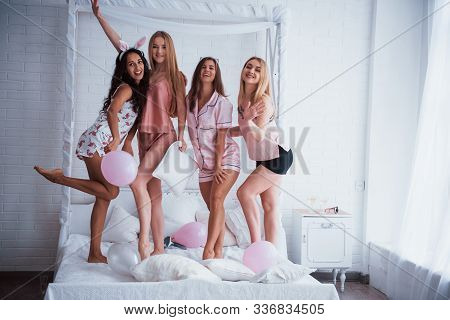 Everyone Looks Into The Camera. Standing On The Luxury White Bad At Holiday Time With Balloons And B