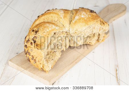 One Whole Sesame Kaiser Roll On Wooden Cutting Board On White Wood