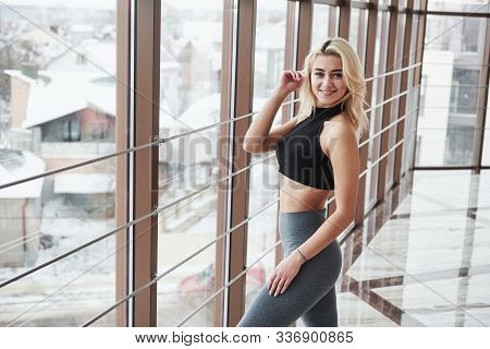 Winter Outside. Gorgeous Blonde Girl In Sportswear Posing In The Gym Near Window.