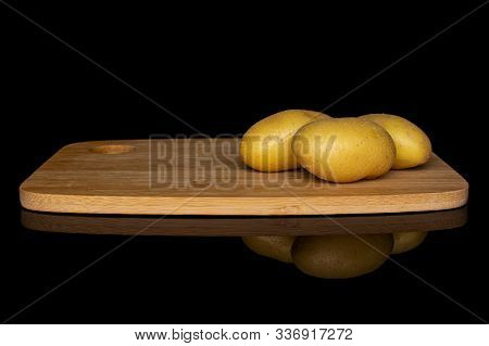 Group Of Three Whole Pale Yellow Potato On Bamboo Cutting Board Isolated On Black Glass
