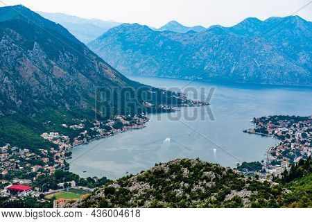 Panorama of Kotor bay and city in Montenegro with aerial view from mountain. Scenic landscape with ancient architectire with red roofs and Adriatic sea