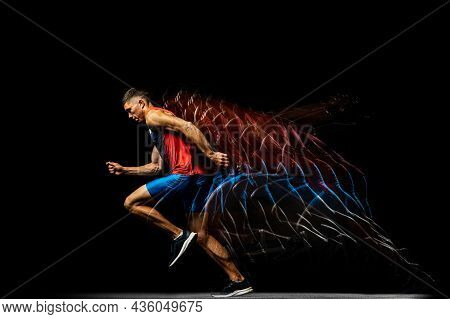 Full-length Portrait Of Young Man, Professional Track Athlete Running, Training Isolated Over Black 
