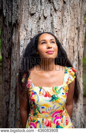 Beautiful Portrait Of A Happy Mixed Race African American Woman Wearing A Yellow Floral Dress Leanin