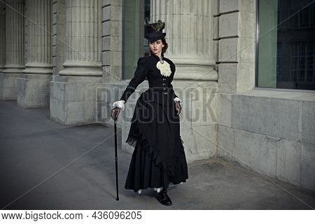 An elegant 19th century lady strolls down a city street. History and Fashion of the late 19th - early 20th century. Full length portrait.