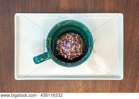 Close Up Top View Of A Hot Cocoa Bomb Covered With Drizzled Brown Chocolate And Purple And White Spr