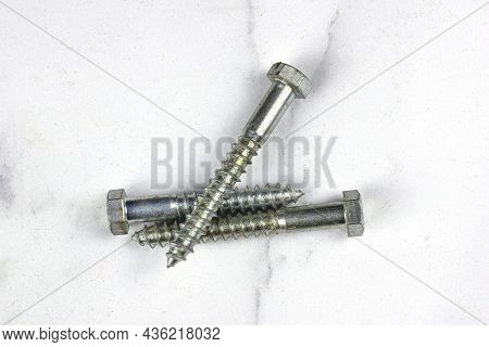 Three Lag Bolts On A White Back Ground.
