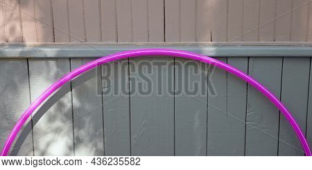 Hulahoop Fragment. Hoop Is Leaned Against Blur Wooden Wall In  Shadow Of Garden Trees. Concept Of Ac