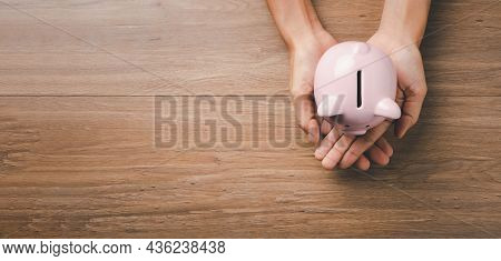 Woman Hand Holding Piggy Bank On Wooden Background, Saving, Charity, Family Finance Plan Concept, Fu