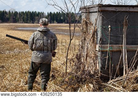 A Duck Hunter Stands Next To The Duck Blind. He Has A Shotgun In His Hands. Before The Hunter Begins