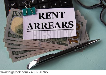 Rent Arrears - Words On A White Piece Of Paper Fixed On Banknotes Against The Background Of A Calcul