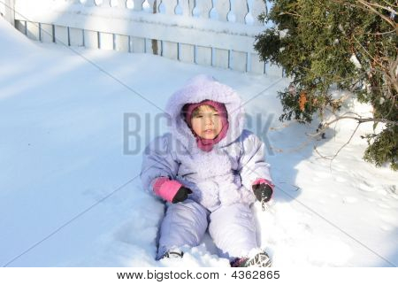 Bebê brincando na neve em tempo muito frio.