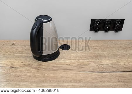 An Electric Kettle Standing On The Countertop On The Kitchen Cabinets, Visible Hole In The Table Top