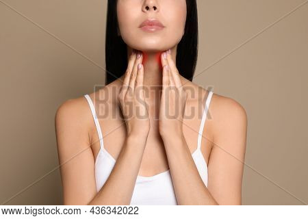 Young Woman Doing Thyroid Self Examination On Beige Background, Closeup