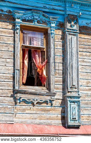 Russian Traditional Wooden Architecture. Facade Of An Old House Decorated With Wooden Carvings, Plat