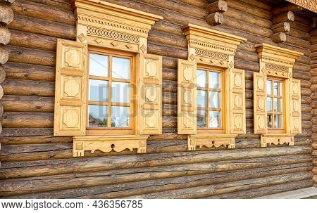 Russian Traditional Wooden Architecture. Windows Of Wooden House Decorated With Wooden Carvings, Pla
