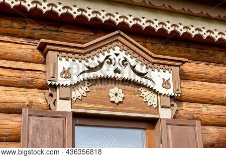 Russian Traditional Wooden Architecture. Windows Of Wooden House Decorated With Wooden Carvings, Pla