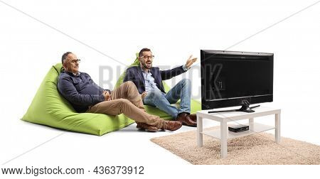 Young and mature man sitting on bean bags and watcing tv isolated on white background