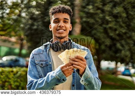 Hispanic young man holding 100 danish krone baknotes at the university campus