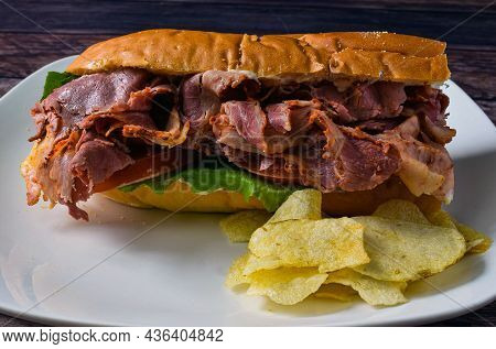 Pastrami Sub With Potato Chips, Against A Black Back Ground