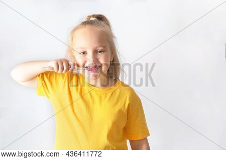 A Blond Girl With Long Hair, 7 Years Old, Brushes Her Teeth.