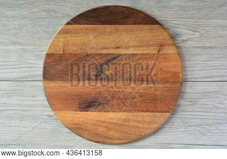 Empty Round Wooden Chopping Board Made From Dark Nutwood, Placed On Light Wooden Kitchen Table, Top 