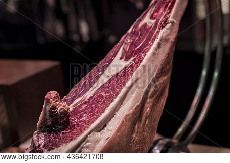 Whole Bone-in Leg Of Spanish Serrano Iberico Ham On A Carving Stand At A Local Butcher Shop In The O