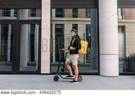 Smiling Messneger Man Standing Outdoors With Electric Push Scooter. Delivery Man With Termal Backpac
