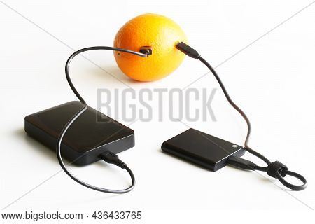 The External Ssd And External Hdd Are Wired To A Fresh Orange. Concept Of Green Technologies, Data S