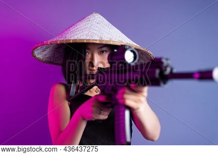 An Asian Woman In An Asian Hat With A Machine Gun Aims