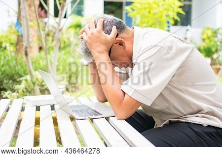 Portrait Of An Old Elderly Asian Man Holds The Head With His Hand Cause Of Stress After Try To Use A