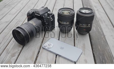 Moscow - Russia, 10.10.2021: New Nikon Camera With Lens And A Modern Iphone 13 Pro Max Lying Outdoor