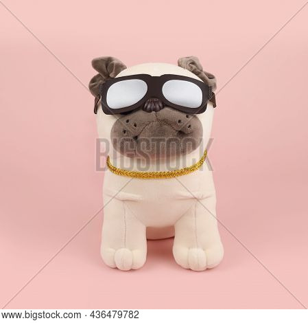 Plush Soft Light Beige Pug Dog Toy With Sun Glasses And Gold Collar Isolated On Pink Background. Fro