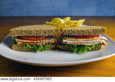 Turky Sanwich Between Wheat Breat And A Side Of Chips,
