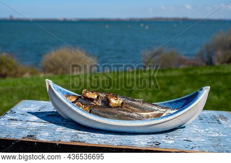 Smoked Sprattus Or Sprats Sea Fish Served Outdoor With View On Blue Sea Water