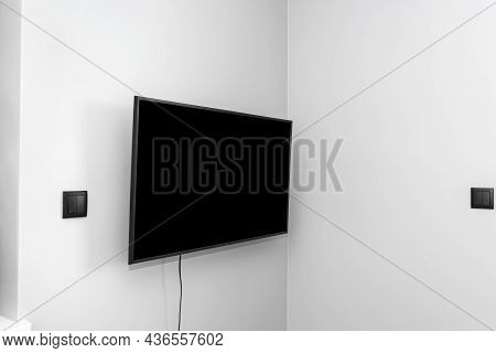 The Tv Is Hung On The Gray Wall In The Bedroom, The Buttons For The Blinds Are Visible.