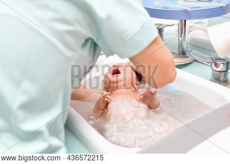 A Nurse Gives The First Bath Of A Newborn Boy
