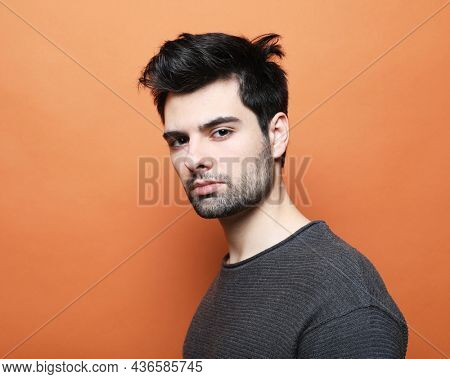 young handsome man posing over orabge background