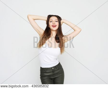Lifestyle, emotion and people concept: Young beautiful brunette woman wearing casual clothes, posing on ligjt grey background.