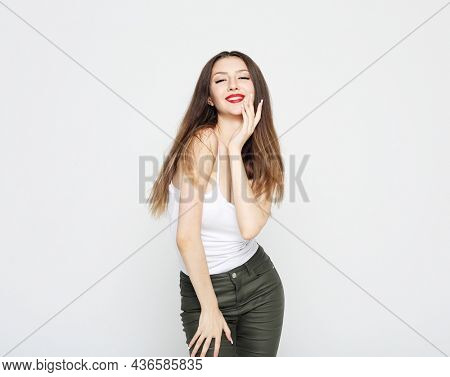 Lifestyle, emotion and people concept: Young beautiful brunette woman wearing casual clothes, posing on ligjt grey background.