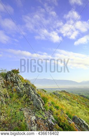 Sharp Rocks On The Top Of A Mountain Above A Mountain Valley Under A Blue Cloudy Sky. Siberia, Russi