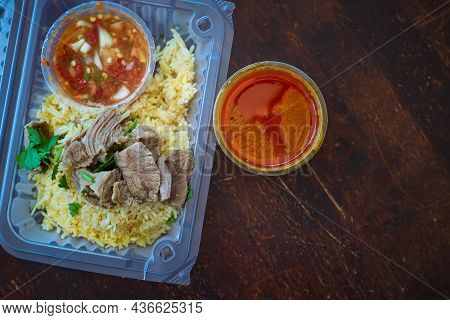 Roasted Meat Served With Rice And Chillies Tamarind Sauce And Curry Gravy In A Take Out Container. M