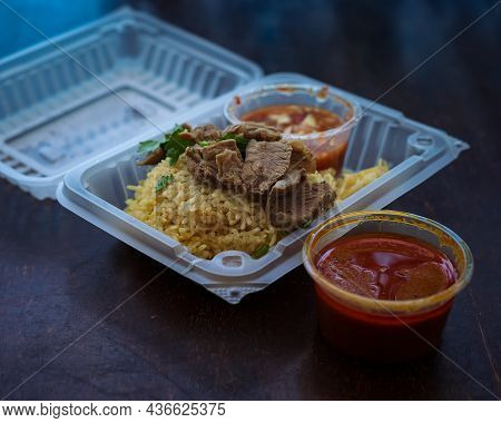 Roasted Meat Served With Rice And Chillies Tamarind Sauce And Curry Gravy In A Take Out Container. M