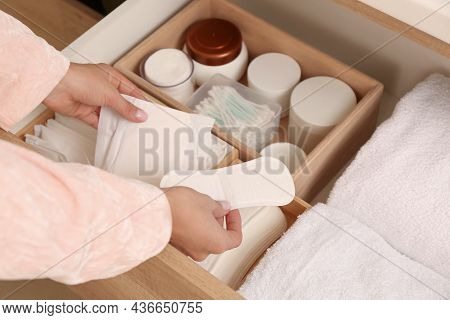Young Woman Taking Menstrual Pad And Pantyliner Out Of Drawer, Closeup
