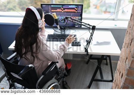 Woman In Wheelchair With Headphones Speaks Into Microphone In Front Of Computer Monitor