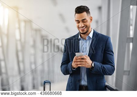 Mobile Communication. Young Handsome Middel Eastern Businessman Using Smartphone In Airport