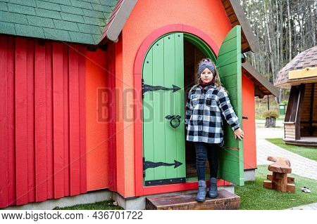 The Girl Comes Out Through The Green Wooden Door Of A Colorful Playhouse